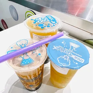 three cups of milk tea and a purple straw