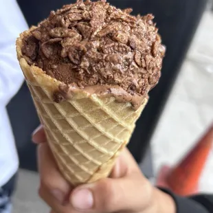 Double chocolate scoop on a cone with chocolate pebbles