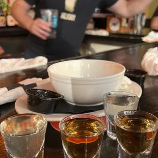 a man at a bar with four shot glasses of whiskey