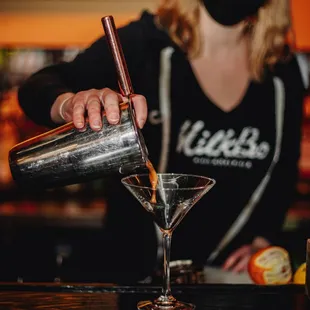 a woman in a mask pouring a martini