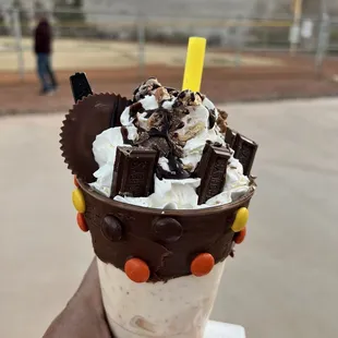 a hand holding a chocolate milkshake