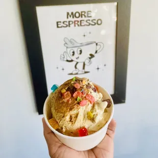 a hand holding a bowl of ice cream