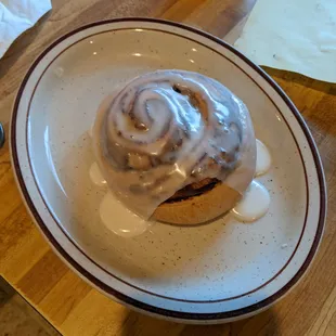 a cinnamon roll with icing on a plate