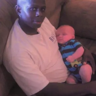 a man sitting on a couch holding a baby