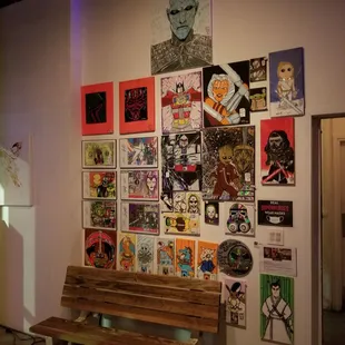 a wooden bench in front of a wall covered with posters