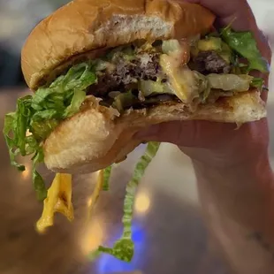 a hand holding a cheeseburger