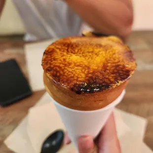 a person holding a pastry in a paper cup