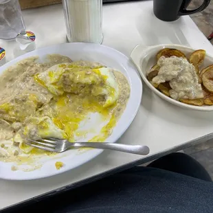 Biscuits &amp; gravy with 2 eggs over easy on top with a side of home fries