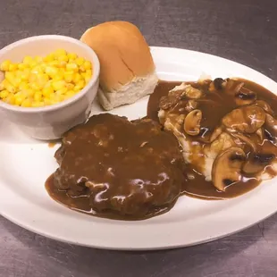 Chopped steak with mashed potatoes covered in gravy and corn