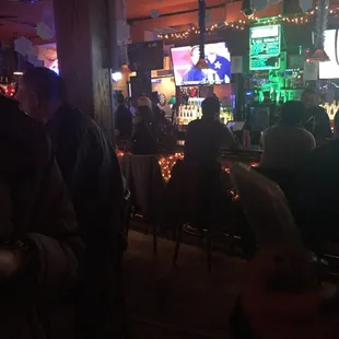 a crowd of people sitting at tables watching televisions