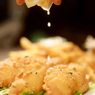 a person squeezing a lemon over a plate of food