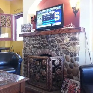 Very cute fireplace with a T.V.. surrounded by some ever comfy chairs.