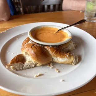 Half eaten beer pretzel with cheese sauce.