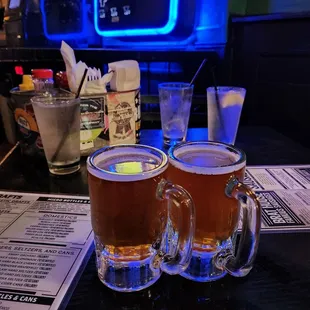 two mugs of beer on a bar