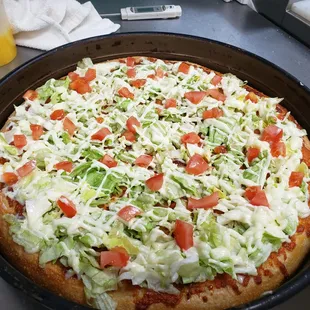 a pizza with lettuce and tomatoes