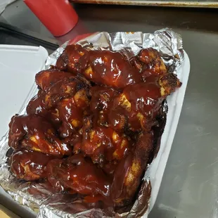 a tray of chicken wings covered in bbq sauce