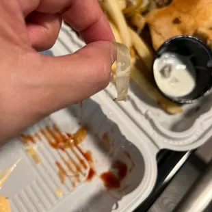 a hand holding a piece of food in a styrofoam container
