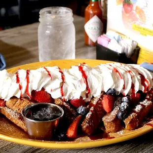 a plate of french toast with strawberries and whipped cream