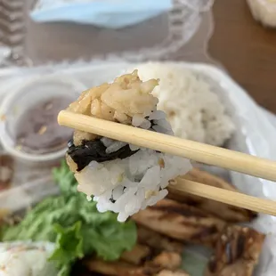 chopsticks holding a piece of sushi