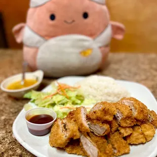 a plate of chicken and rice with a stuffed toy in the background