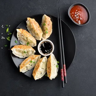 a plate of dumplings with dipping sauce and chopsticks