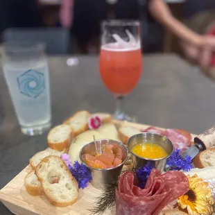 a platter of meats, breads, and drinks