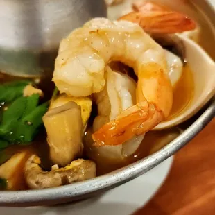 a bowl of soup with shrimp and vegetables