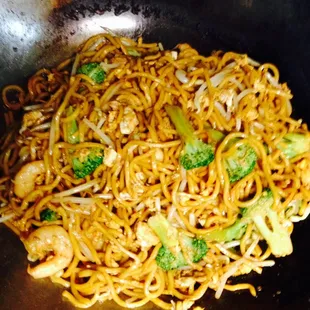 a wok of noodles and broccoli