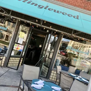the outside of a restaurant with tables and chairs