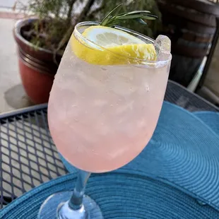 a pink drink with lemon and rosemary garnish