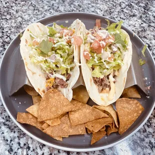 two tacos on a plate with tortilla chips