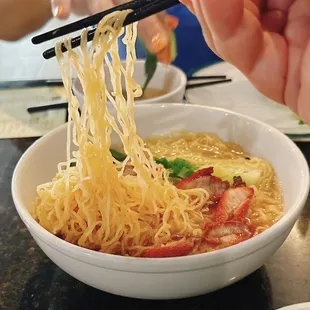 a bowl of noodles with chopsticks
