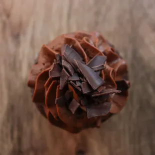 a chocolate frosted cupcake on a wooden table