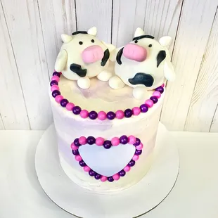 two cows on top of a cake