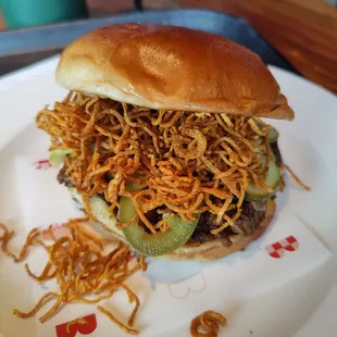 a hamburger with shredded cheese and pickles