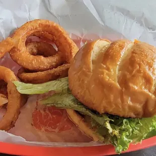 Cheeseburger with added lettuce, tomato and onion and onion rings.
