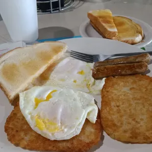 Traditional Breakfast eggs over easy sourdough toast link sausage Strawberry jam and Newspaper
