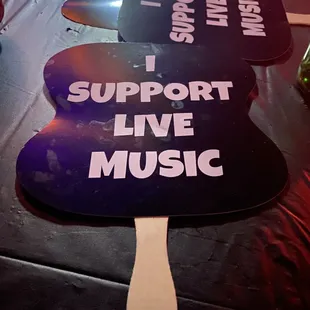 two fans with i support live music written on them