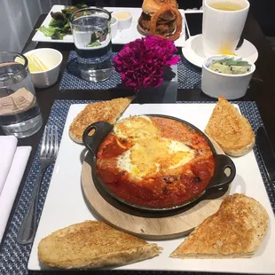 Shakshuka (front) , quinoa veggie burger comes with salad and a onion ring (back), hot green tea (right)