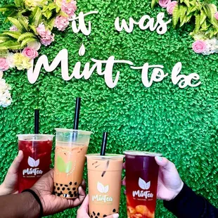 three people holding drinks in front of a sign that says it was mint tea