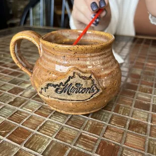 a woman sitting at a table with a mug and a toothbrush