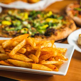 a plate of french fries and a plate of pizza