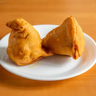 two fried pastries on a white plate