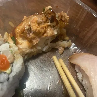 a close up of a plate of sushi with chopsticks