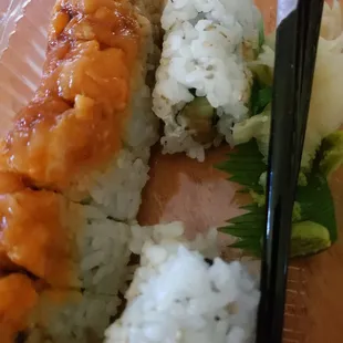 a close up of a plate of sushi with chopsticks