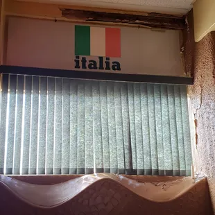 a window with blinds and a sign that says italia