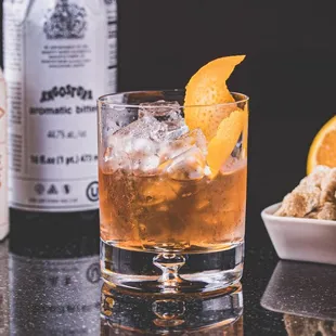 a glass of orange bitter next to a bottle of orange bitter