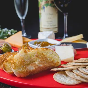 a platter of cheese, crackers, olives and bread