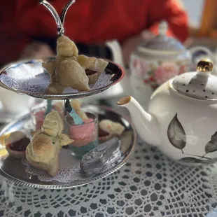 a table with a teapot, teacups, and cookies