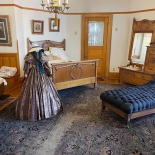 a bedroom with a bed, dressers, and a chair